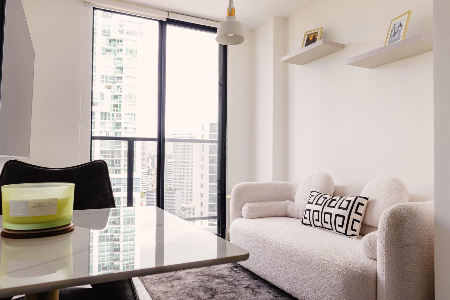 Sala luminosa con sofá blanco y ventanal hacia edificios