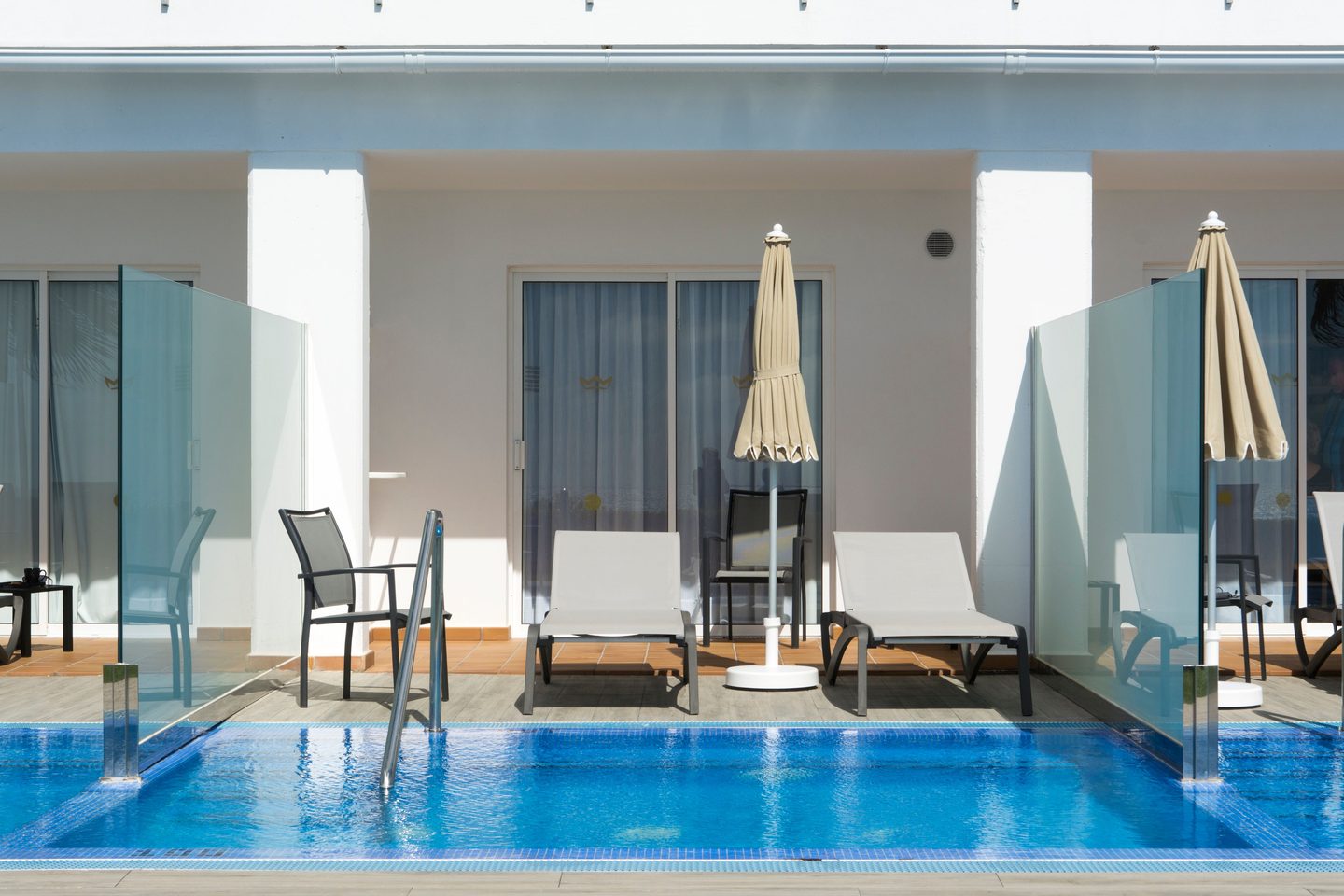 Piscina con tumbonas y sombrillas frente al edificio