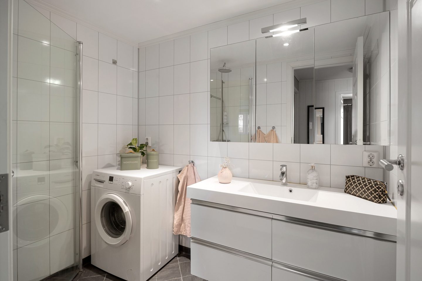 Baño blanco con mueble suspendido y lavadora
